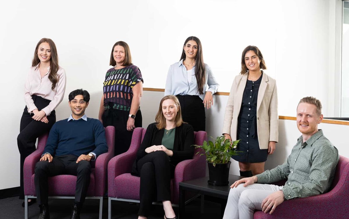 Group photo of 2023 MACH-Track cohort standing around around and seated at a couch.